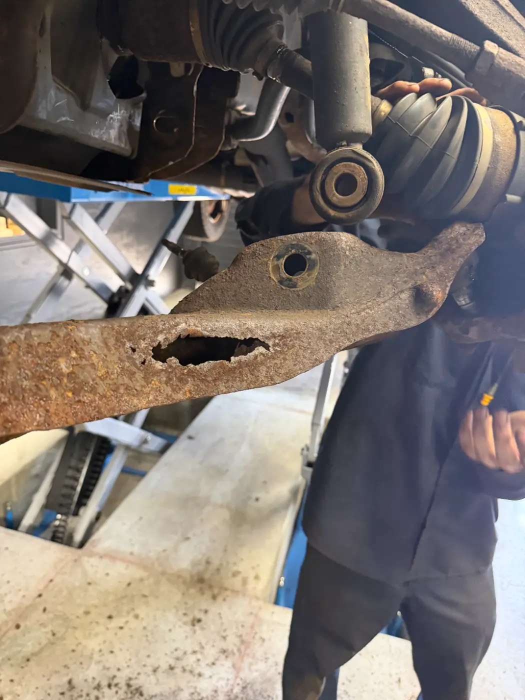 Technician holding a Ford F150 lower control arm rotted through, found during an oil change at our South Windsor shop