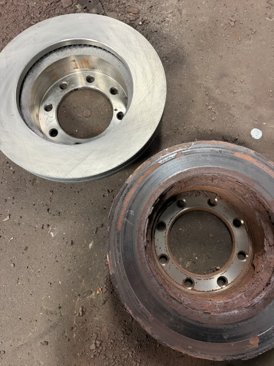 Old rusted rotor next to a new rotor from a Ford F250 brake job at our South Windsor shop