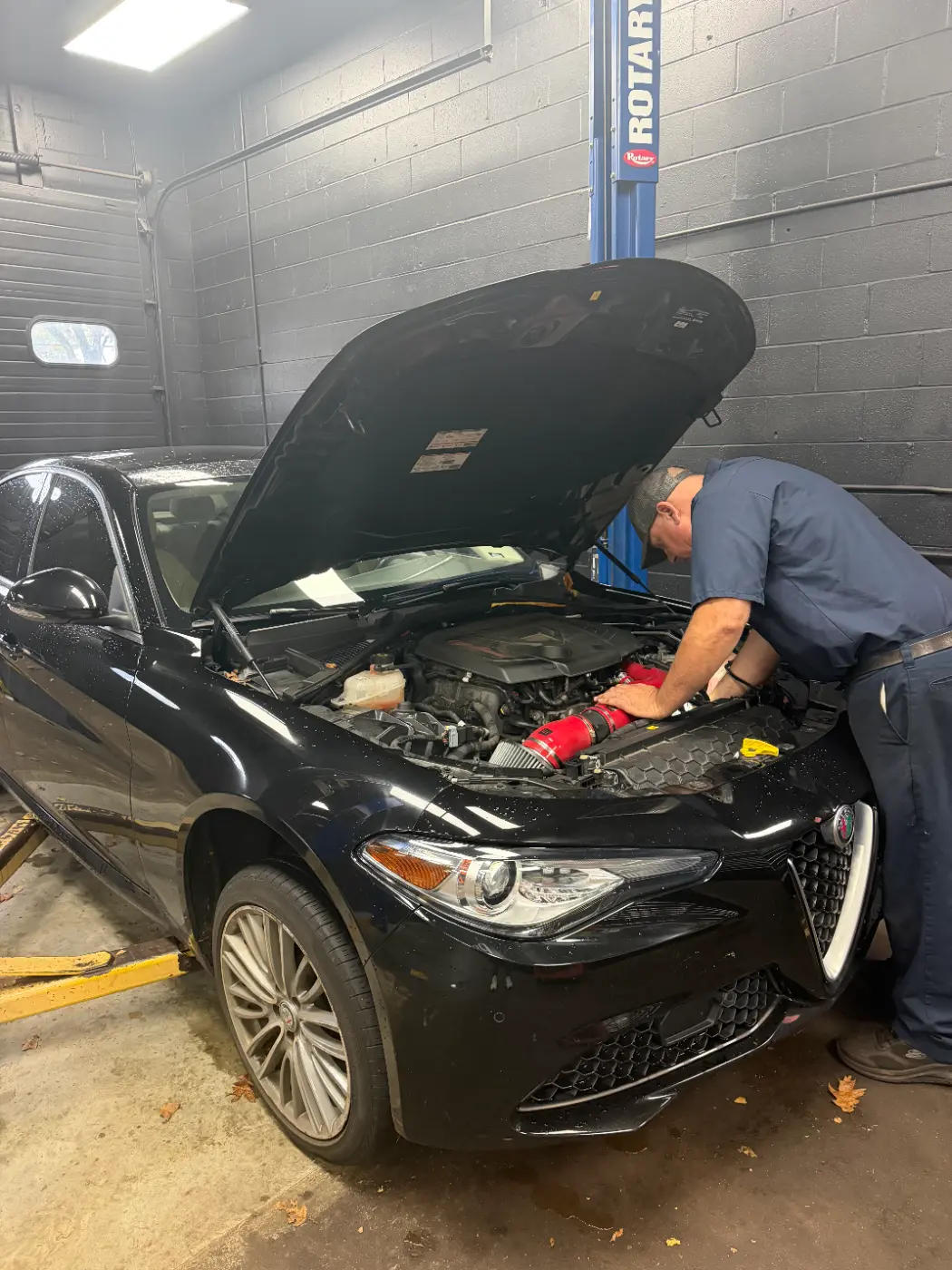 Technician working under the hood of an Alfa Romeo at our West Springfield shop