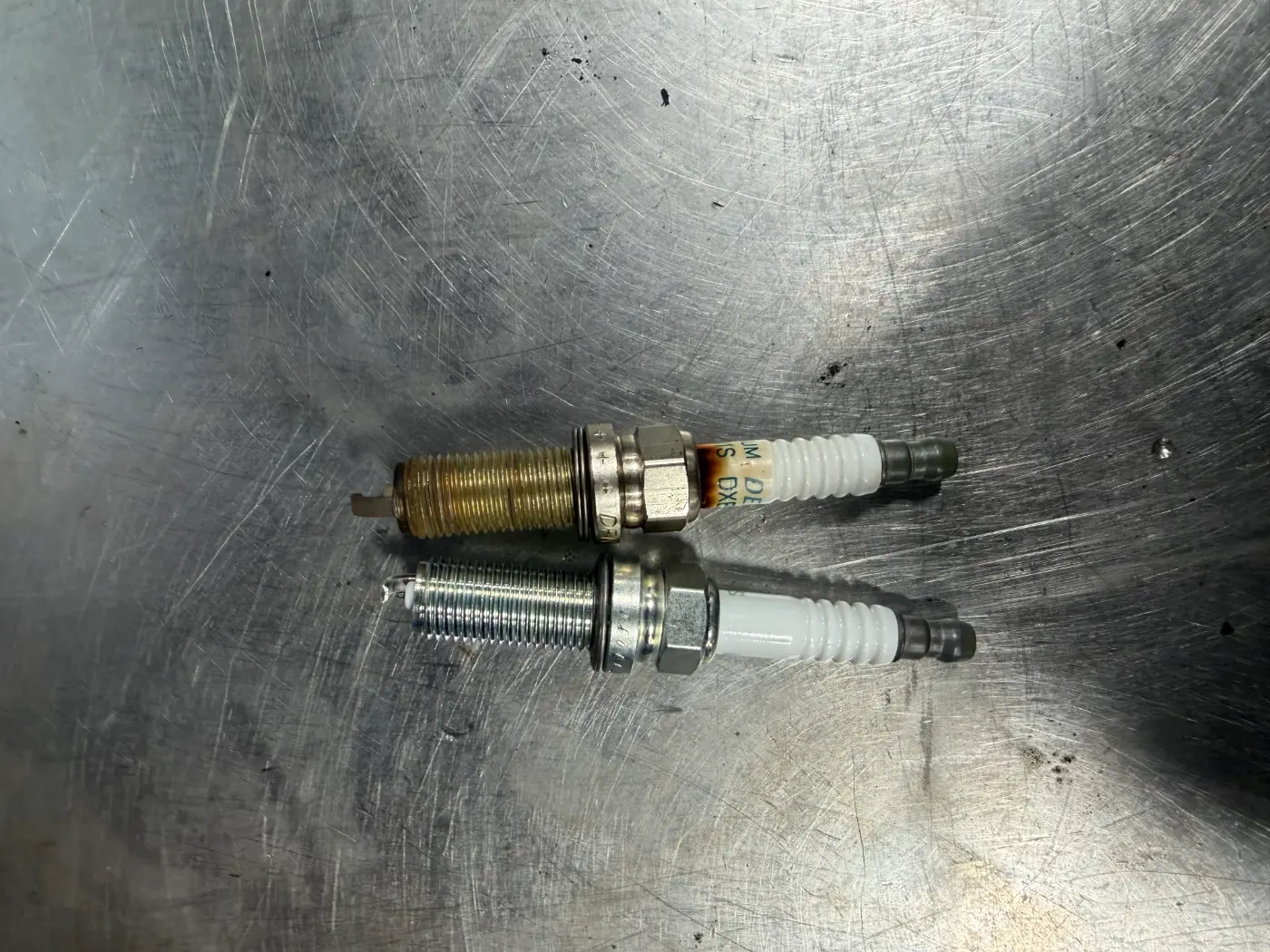 Old spark plug next to a new one, replaced for a misfire and bad gas mileage at our West Springfield shop
